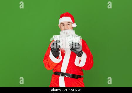 Un uomo caucasico adulto vestito come Babbo Natale è in possesso di tre $ 50 fatture. Lo sfondo è verde. Foto Stock