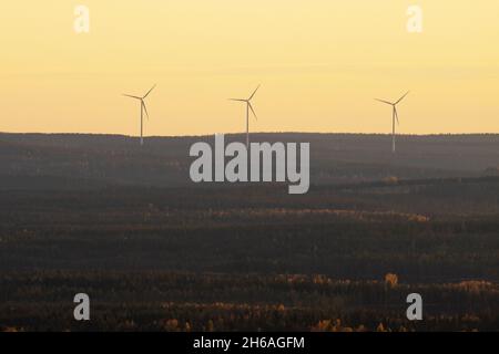 Tre turbine eoliche che lavorano nella Finlandia settentrionale durante una serata buia. Foto Stock