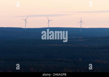 Tre turbine eoliche che lavorano nella Finlandia settentrionale durante una serata buia. Foto Stock