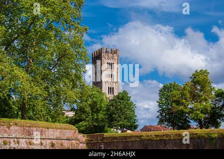 Lucca affascinante centro storico. Vista dell'iconico campanile medievale di San Frediano con le antiche mura della città Foto Stock