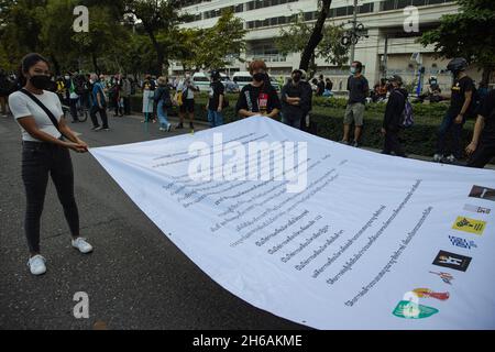 Bangkok, Tailandia. 14 novembre 2021. I manifestanti hanno un grande bandiera durante la dimostrazione.i dimostranti pro-democrazia si sono riuniti all’incrocio di Pathumwan per una campagna “lotta contro la monarchia assoluta”. Questa campagna è giunta dopo un verdetto della Corte costituzionale, giudicato che tre discorsi di “riforma della monarchia” il 10 agosto 2020 è “annientare la monarchia costituzionale”. I manifestanti chiedono la riforma della monarchia e l'abolizione di una sezione di diritto penale 112 (lèse-majesté). (Foto di Varuth Pongsapipatt/SOPA Images/Sipa USA) Credit: Sipa USA/Alamy Live News Foto Stock