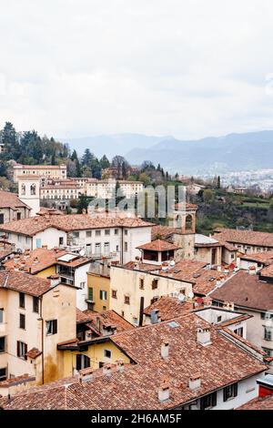 Tetti di tegole delle vecchie case bergamasche sullo sfondo delle montagne. Italia Foto Stock