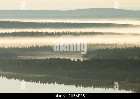 Belle campane nella nebbia durante una mattina tranquilla vicino a un lago nella Finlandia settentrionale vicino Kuusamo in autunno. Foto Stock