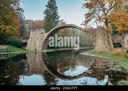 Unico Looking ponte Rakotzbrucke, chiamato anche Devils Bridge, Sassonia, Germania. Costruito per creare cerchio quando si riflette in Waters.colorful caduta Foto Stock