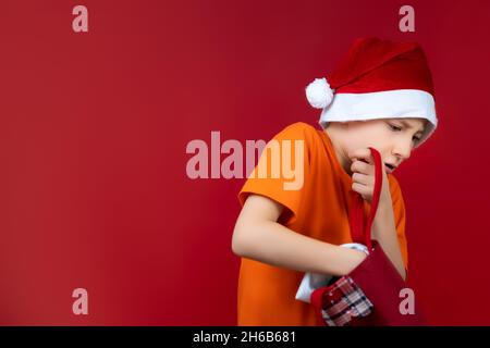 Un ragazzo con una borsa di Natale rummages in cerca di regali Foto Stock