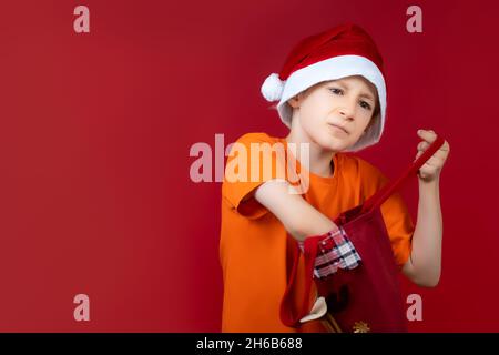 Un ragazzo con una borsa di Natale rummages in cerca di regali Foto Stock