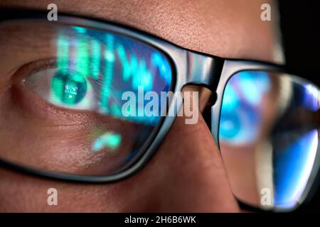Trader guardando lo schermo del calcolatore che analizza la tabella di commercio che riflette negli occhiali. Foto Stock