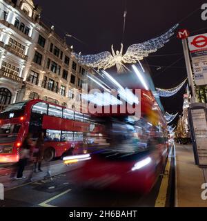 Londra, Greater London, Inghilterra, 13 2021 novembre: Mostra di luci natalizie su Regent Street di notte mentre passano gli autobus. Foto Stock