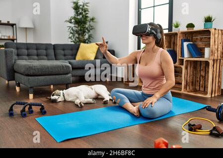 Giovane donna sorridente allenata con sicurezza utilizzando occhiali per realtà virtuale a casa Foto Stock