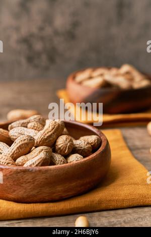 Immagine di un mazzo di arachidi in una ciotola su un tavolo di legno Foto Stock