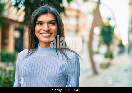 Bella donna ispanica sorridente confidente in città Foto Stock