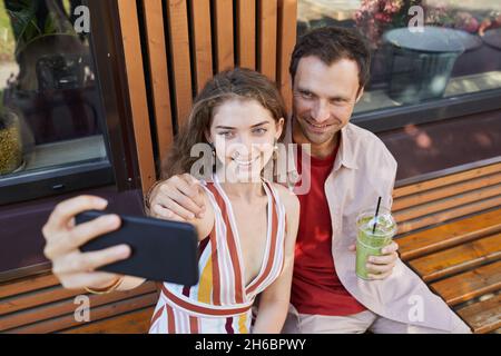Ritratto ad angolo alto di giovane coppia scattare foto selfie all'aperto mentre godendo insieme data, spazio copia Foto Stock