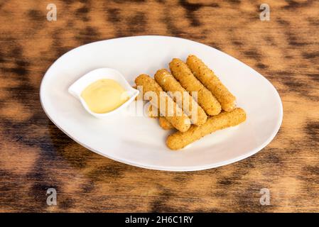 Razione di mozzarella in padella e fritta in olio d'oliva con salsa di maionese per l'immersione su un piatto bianco Foto Stock