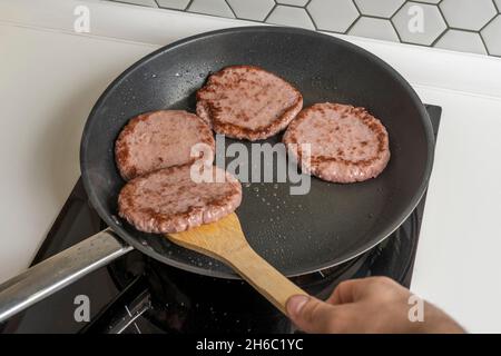 cottura degli hamburger di manzo su una padella antiaderente Foto Stock