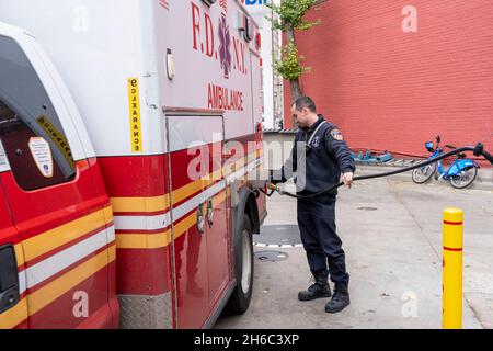 NEW YORK, NY – 14 NOVEMBRE: Un tecnico medico di emergenza FDNY alimenta un'ambulanza in una stazione di benzina mobile il 14 novembre 2021 a New York City. Stando in piedi di fronte ad una stazione di benzina Mobil sulla 8th Avenue nel West Village, i prezzi iniziano a $4.33 un gallone per un gallone di 87 ottani di benzina, il leader della maggioranza del Senato degli Stati Uniti il senatore Chuck Schumer (D-NY) dice che i conducenti di New York hanno disperatamente bisogno del rilievo dall'aumento dei prezzi del carburante. Il senatore Schumer spera che sfruttare la Riserva strategica del petrolio della nazione contribuirebbe a ridurre i costi del carburante per un po'. Foto Stock