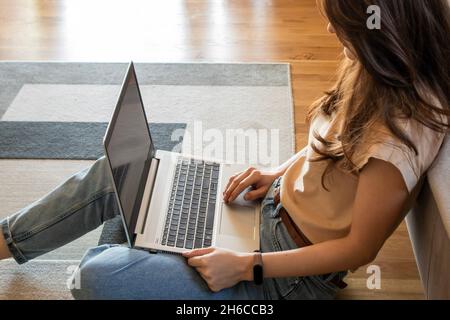 Primo piano di una donna che lavora da casa in remoto con un notebook su un divano Foto Stock