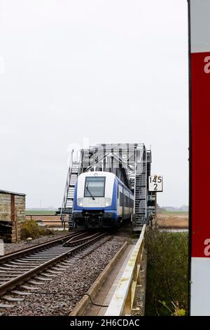 Friedrichstadt, Germania. 14 novembre 2021. Un treno regionale espresso attraversa il ponte ferroviario vicino a Friedrichstadt sulla linea Marschbahn. Il 1° novembre 2021, l'espansione della capacità della Marschbahn, finanziata dallo Stato di Schleswig-Holstein e Deutsche Bahn, è giunta al termine. L'obiettivo era quello di fornire più seggi. Credit: Frank Molter/dpa/Alamy Live News Foto Stock