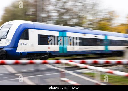 Friedrichstadt, Germania. 14 novembre 2021. Un treno regionale espresso passa attraverso Friedrichstadt ad un incrocio a livello. Il 1° novembre 2021, l'espansione della capacità della Marschbahn, finanziata dallo Stato di Schleswig-Holstein e Deutsche Bahn, è giunta al termine. L'obiettivo era quello di fornire più seggi. Credit: Frank Molter/dpa/Alamy Live News Foto Stock