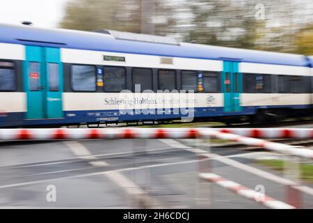 Friedrichstadt, Germania. 14 novembre 2021. Un treno regionale espresso passa attraverso Friedrichstadt ad un incrocio a livello. Il 1° novembre 2021, l'espansione della capacità della Marschbahn, finanziata dallo Stato di Schleswig-Holstein e Deutsche Bahn, è giunta al termine. L'obiettivo era quello di fornire più seggi. Credit: Frank Molter/dpa/Alamy Live News Foto Stock