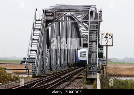 Friedrichstadt, Germania. 14 novembre 2021. Un treno regionale espresso attraversa il ponte ferroviario vicino a Friedrichstadt sulla linea Marschbahn. Il 1° novembre 2021, l'espansione della capacità della Marschbahn, finanziata dallo Stato di Schleswig-Holstein e Deutsche Bahn, è giunta al termine. L'obiettivo era quello di fornire più seggi. Credit: Frank Molter/dpa/Alamy Live News Foto Stock