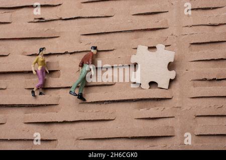 pezzo di puzzle e minuscola figurina di uomo e donna miniatura modello in vista Foto Stock