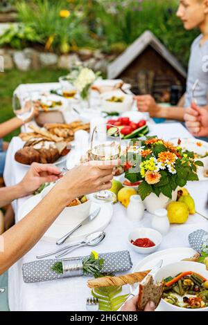 Una cena in famiglia o un barbecue nel giardino estivo. Divertimento in famiglia, celebrazione e concetto di cibo. La gente sta mangiando ad un partito del giardino. Barbecue, v Foto Stock