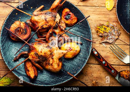 Gustosa quaglia fatta in casa grigliata su spiedini in salsa di frutta. Foto Stock