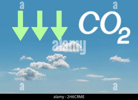 Ridurre le emissioni di anidride carbonica, limitare il riscaldamento globale e il concetto di cambiamento climatico. Segno CO2 e frecce verdi che puntano verso il basso sul cielo blu con le nuvole Foto Stock