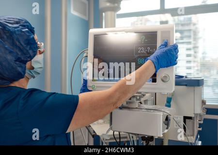 chirurgo che tiene traccia delle funzioni vitali del corpo durante la chirurgia cardiaca. Chirurgo che guarda il monitor medico durante l'intervento chirurgico. Medico controllo monito Foto Stock