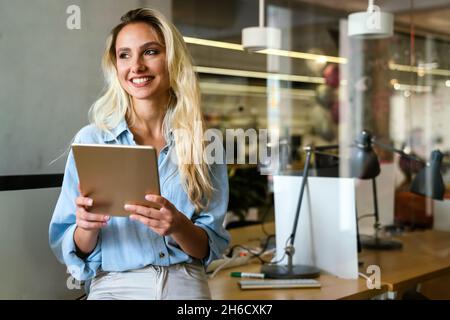 Ritratto di felice donna di successo che lavora, websurf su tablet digitale in ufficio Foto Stock