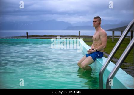 Bagni per ragazzi nella piscina riscaldata di Reykjafjardarlag, situata a Westfjords, Islanda Foto Stock