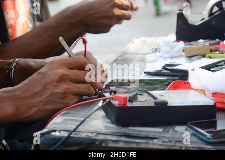 un tecnico sta controllando un cellulare utilizzando un misuratore avo Foto Stock