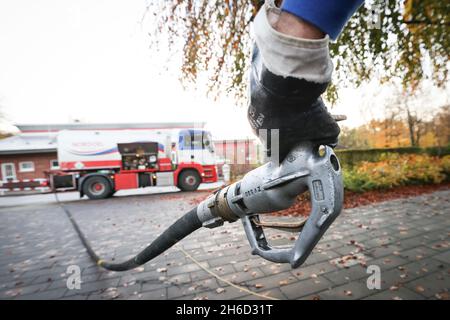 Itzehoe, Germania. 9 novembre 2021. Un dipendente di un'azienda produttrice di gasolio e olio di riscaldamento tiene l'ugello per la consegna di olio di riscaldamento a un cliente in un edificio di appartamenti. Credit: Christian Charisius/dpa/Alamy Live News Foto Stock