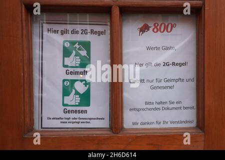Potsdam, Germania. 15 Nov 2021. Un cartello che indica la conformità alla regola 2G è visibile sulla porta d'ingresso di un ristorante. A Brandeburgo entrano in vigore le più severe norme Corona. La regola del 2G con accesso solo per le persone vaccinate e ricoverate diventa obbligatoria per alcune aree, più un requisito di maschera nelle scuole primarie. Credit: Jörg Carstensen/dpa/Alamy Live News Foto Stock
