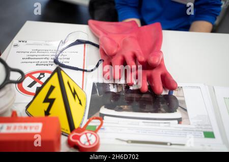 PRODUZIONE - 12 novembre 2021, Hessen, Francoforte sul meno: Sul tavolo sono presenti guanti isolanti da indossare prima di intervenire su un veicolo elettrico. Foto: Frank Rumpenhorst/dpa Foto Stock