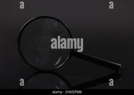Primo piano della lente di ingrandimento su sfondo nero Foto Stock