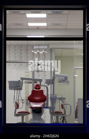 nuovo ufficio dentale. odontoiatria notturna. sedia dentale rossa, vista dalla finestra Foto Stock