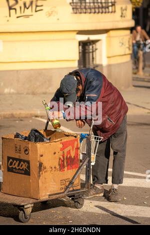 Senzatetto che tiene in mano una bottiglia spingendo un carrello per strada. Concetto di disperazione. Sofia Bulgaria, Europa orientale, Balcani, UE Foto Stock