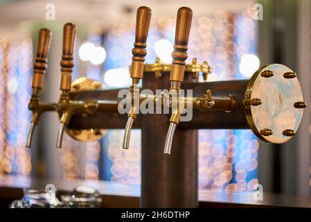 Primo piano dei rubinetti di birra su sfondo dorato bokeh. Foto Stock