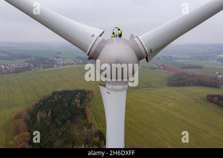 Bernsdorf, Germania. 15 Nov 2021. Due tecnici della Sabowind GmbH gestiscono una turbina eolica Enercon E92. Lo stesso giorno, la campagna 'Energieland Sachsen. Rinnovare insieme". La campagna intende utilizzare esempi concreti per dimostrare perché l'economia della Sassonia ha bisogno di energia verde e come le imprese e i cittadini sassoni possono trarre vantaggio dalla transizione energetica. (Vista aerea con drone) Credit: Jan Woitas/dpa-Zentralbild/dpa/Alamy Live News Foto Stock