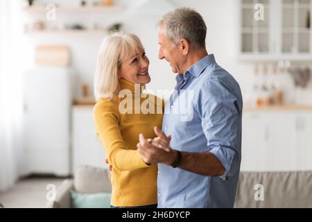Amorevole coppia anziano ballando a casa Holding Hands avere Data Foto Stock