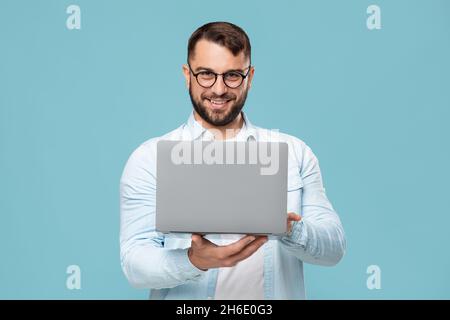 Uomo d'affari europeo felice adulto in occhiali che lavorano su un portatile o fanno videochiamate Foto Stock