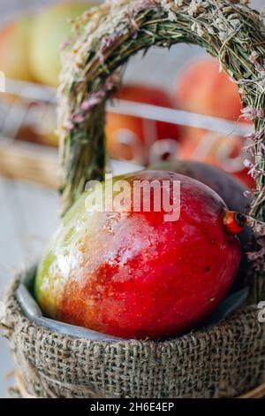 Mango maturo in un cestino su sfondo bianco di legno Foto Stock