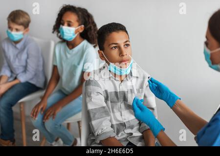 African American Boy Getting saggied for Covid-19 Antigen in Clinic Foto Stock