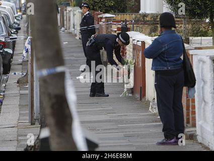 La famiglia e gli amici visitano la scena dove un ragazzo di 15 anni è morto di ferite da pugnale dopo un attacco di coltello per strada. I detective stanno cacciando i suoi attaccanti che hanno messo sopra l'adolescente a Edmonton, Londra del nord, la notte scorsa. Egli è il quarto adolescente a morire nella capitale quest'anno. Foto Stock
