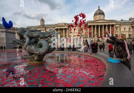 I membri del pubblico gettano papaveri nelle fontane in Trafalgar Square Foto Stock