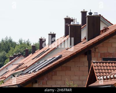 Tetti di molte case residenziali di recente costruzione in Germania con camini per il riscaldamento centrale a gas o a petrolio. Foto Stock