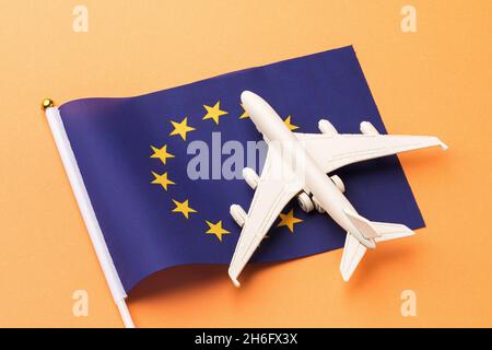 Bandiera dell'UE e aereo giocattolo su sfondo arancione, concetto di voli per l'Unione europea Foto Stock