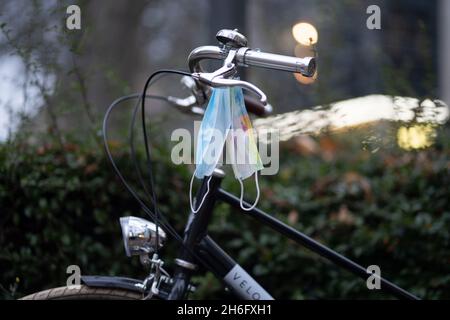 15 novembre 2021, Hessen, Francoforte sul meno: Due maschere dangle dal manubrio di una bicicletta in serata nel quartiere di Bockenheim. Foto: Frank Rumpenhorst/dpa Foto Stock