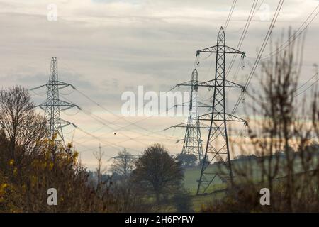 I piloni elettrici attraversano la campagna del Pennine vicino Halifax, Calderdale, West Yorkshire. Una torre di trasmissione, nota anche come pilone elettrico o semplicemente come pilone inglese britannico e come idro torre in inglese canadese, è una struttura alta, solitamente una torre reticolare in acciaio, utilizzata per sostenere una linea elettrica aerea. Nelle reti elettriche, esse sono generalmente utilizzate per trasportare linee di trasmissione ad alta tensione che trasportano energia elettrica di massa dalle stazioni di generazione alle sottostazioni elettriche. Foto Stock